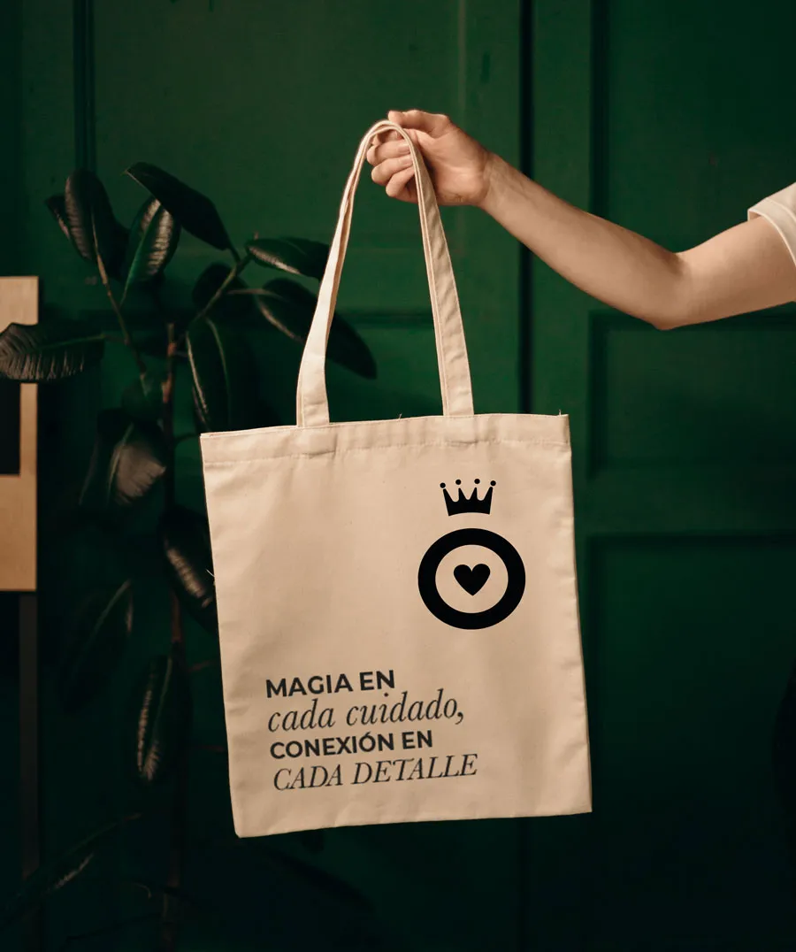 Bolsa de tela con el logo de la corona y el lema «Magia en cada cuidado, conexión en cada detalle»