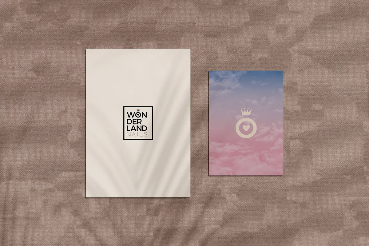 Papelería de Wonderland Nails con el logo en cuadro sobre fondo rosa y arena